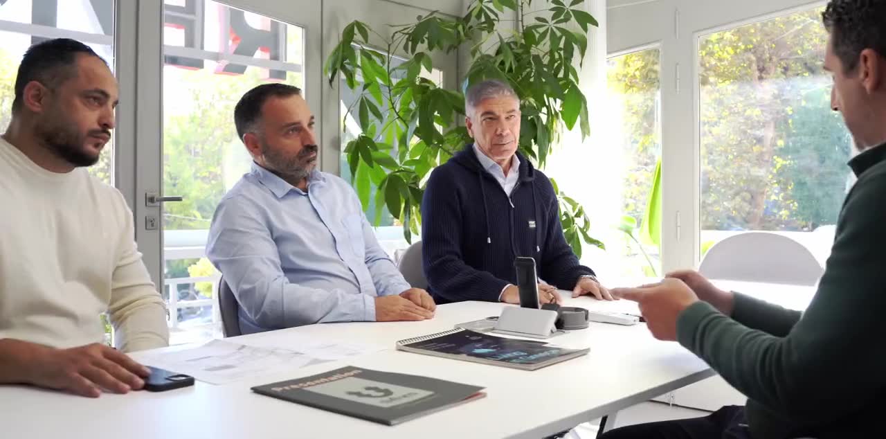 Συνεργάτες της REMAX delta-ktima συζητούν γύρω από ένα τραπέζι στο γραφείο